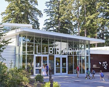 Adults and kids loaded with backpacks walk up to Cascade Park Community Library