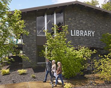 Pedestrians walk past the stone facade of Stevenson Community Library