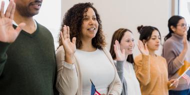 People with right hand raised holding small US flags